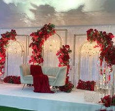 a white couch sitting on top of a lush green field next to a red rose covered wall