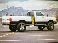 a white truck parked in a parking lot with mountains in the backgroup