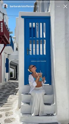 a woman sitting on steps in front of a blue door