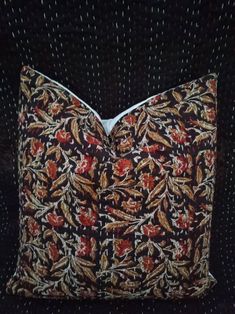 a close up of a decorative pillow on a black background with red and yellow flowers