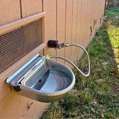 an outdoor water fountain attached to the side of a building with a hose connected to it