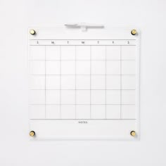 a white board with gold studs on the sides and a calendar attached to it