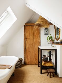 an attic bedroom with a white bathtub and wooden cabinet in the corner next to it