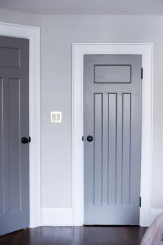 two gray doors in a white room with hardwood floors