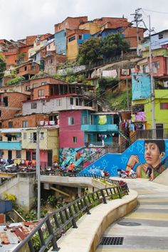 a city with lots of colorful buildings and graffiti on the walls, along with stairs leading up to an overpass