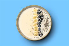 a banana and blueberry smoothie in a bowl on a blue background with sprinkles