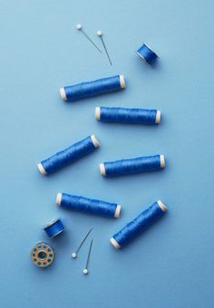 sewing needles and thread on a blue surface