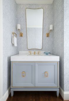 a bathroom vanity with two sinks and a large mirror above it in a blue wallpapered room