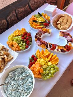 a table topped with plates of food and bowls of dips next to crackers