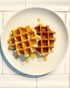 two waffles on a white plate with syrup