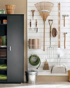 an organized garage with tools and cleaning supplies on the wall next to a storage cabinet