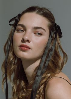 a woman with long hair wearing a black ribbon around her head and looking off to the side