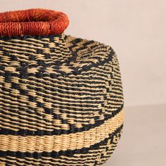 a close up of a woven basket on a white surface with orange and black stripes