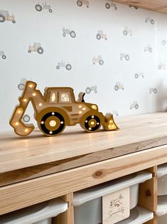 a wooden table topped with drawers and a light up toy truck on top of it