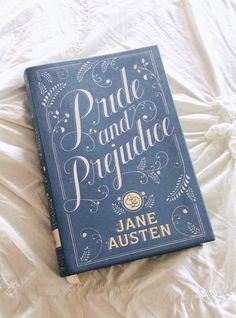 a blue book sitting on top of a white bed covered in sheets and pillows with the title pride and progjudicc written above it