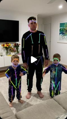 a man standing next to two small children in pajamas on top of a carpeted floor