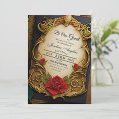 a card with an ornate frame and red rose on it, sitting next to a vase filled with flowers