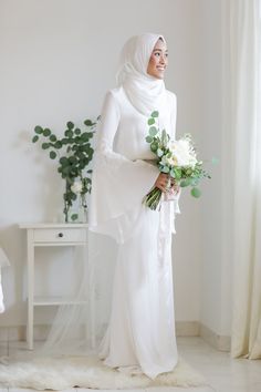 a woman in a white hijab holding a bouquet of flowers