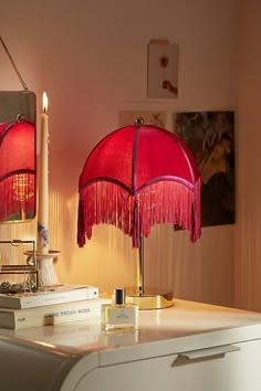 two red lamps sitting on top of a table next to a white dresser and mirror