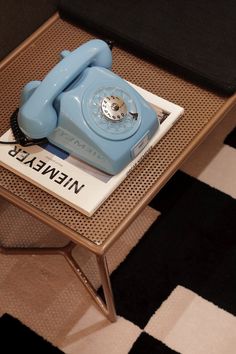 a blue phone sitting on top of a coffee table next to a black and white checkered floor