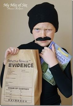 a young boy wearing a black hat and holding a brown paper bag with evidence on it