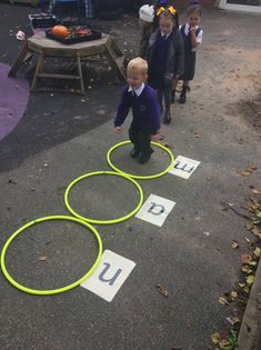 three children are playing with hula hoops on the ground