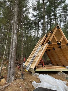 a wooden structure in the middle of a forest with lots of wood on it's sides