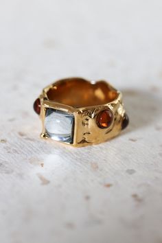 Edna Surrealist Gemstone Molten Gold Ring features a warm molten gold band with multiple colorful gemstones set on top. Make a statement with this ring! Each of the textured bands is genuinely unique. ◊ 18k Gold Plated over Brass ◊ Each piece is unique and may have surface irregularities. ◊ Costume jewelry gems. The gems are glued on, please beware of the jewels falling. ◊ Band thickness measures approx. 9mm ◊ Delivered in our signature royal blue box, it makes the perfect gift! SAY HI TO US Ins Thick Gold Ring, Textured Gold Ring, Molten Gold, Vintage Gold Rings, Statement Rings Diamond, Gold Elephant, Artisan Gift, Recycled Jewelry