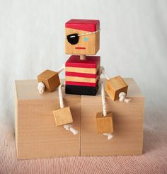 a small wooden toy sitting on top of a piece of wood next to some string