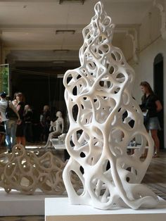 a group of people standing around a white sculpture