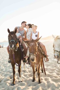 a group of people riding on the back of horses in the sand at the beach