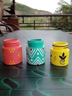 three painted jars sitting on top of a table