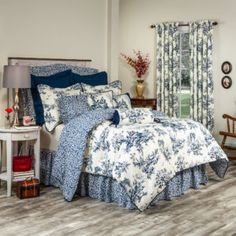 a bed with blue and white comforter in a bedroom next to a window covered by curtains