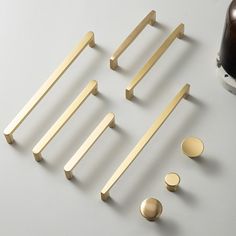 several brass handles and knobs on a white surface next to a bottle of beer