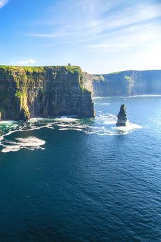 an aerial view of cliffs on the ocean with waves coming in from the water and blue sky