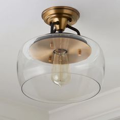 a light fixture with a clear glass bowl on the bottom and an antique brass finish