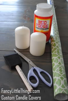 scissors, candles, and glue sitting on a table next to a roll of fabric