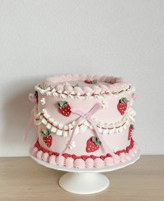 a pink cake decorated with strawberries and ribbons