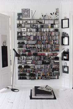 a book shelf filled with lots of books on top of a white wall next to a lamp