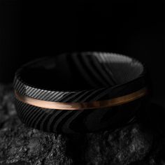 a black and gold bracelet sitting on top of a rock