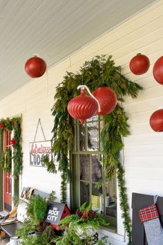 the front porch is decorated for christmas with wreaths and pomegranates