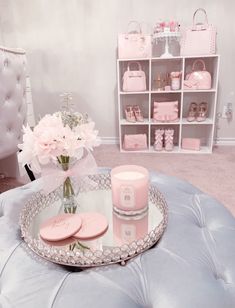 a table with pink items on it and flowers in a vase next to the tray