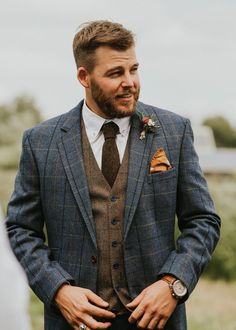 a man in a suit and tie standing next to another man wearing a flower on his lapel