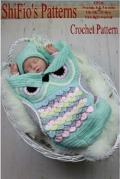 a baby in a blue knitted owl outfit laying on top of a white basket