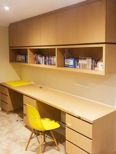 a desk with two yellow chairs next to it and bookshelves on the wall