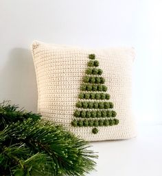 a crocheted christmas tree pillow sitting on top of a table next to a plant