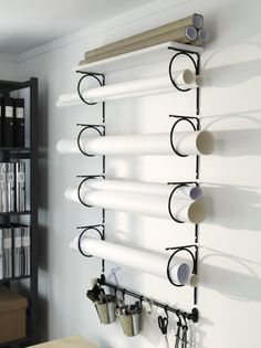 a wall mounted shelf with several glasses hanging on it's sides and some bookshelves in the background