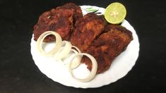 two pieces of chicken on a plate with onion rings