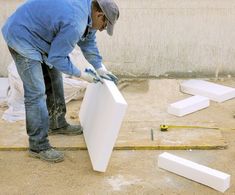 a man in blue shirt and jeans working on an unfinished piece of white plastic furniture