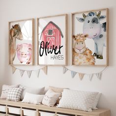 three farm animals are hanging on the wall above a bench with pillows and pillow cases